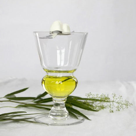 absinthe glass, absinthe in glass, spoon and sugar on glass, scattered green leaves, white background.