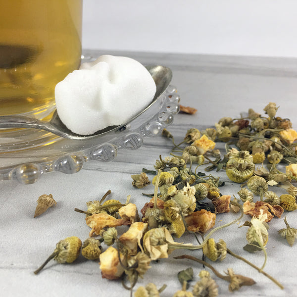 Close up of Herbal Tea scattered on light background, Brightly lit with clear tea cup and skull sugar cube  on silver spoon